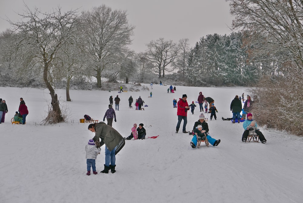 pessoas sentadas no chão coberto de neve durante o dia