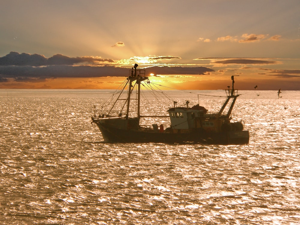 black ship on sea during sunset