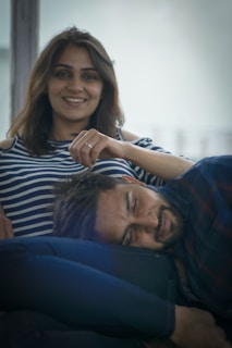 A cozy scene of a man resting his head in a woman's lap as she strokes his hair softly.
