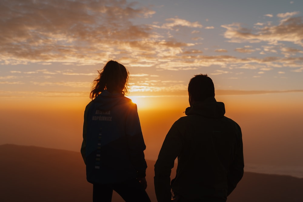 silhouette of man and woman standing during sunset