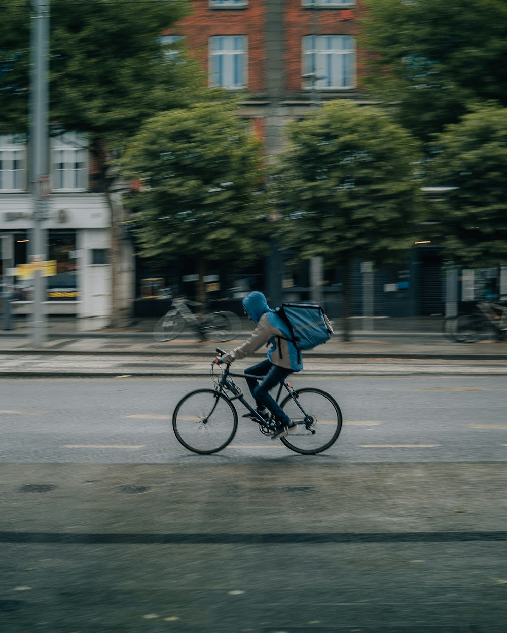 昼間、道路を自転車で走る青いシャツを着た男性