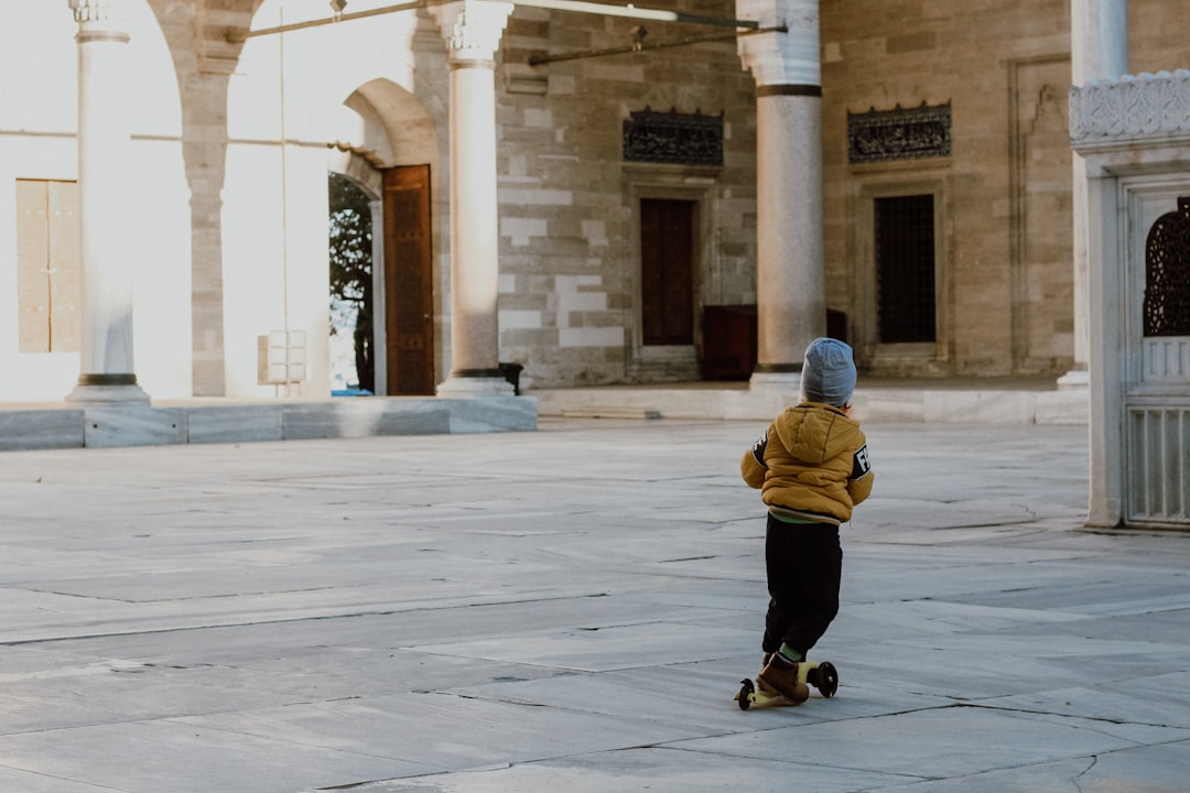 person in yellow jacket walking on gray concrete pathway during daytime