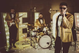 man in black suit standing near drum set