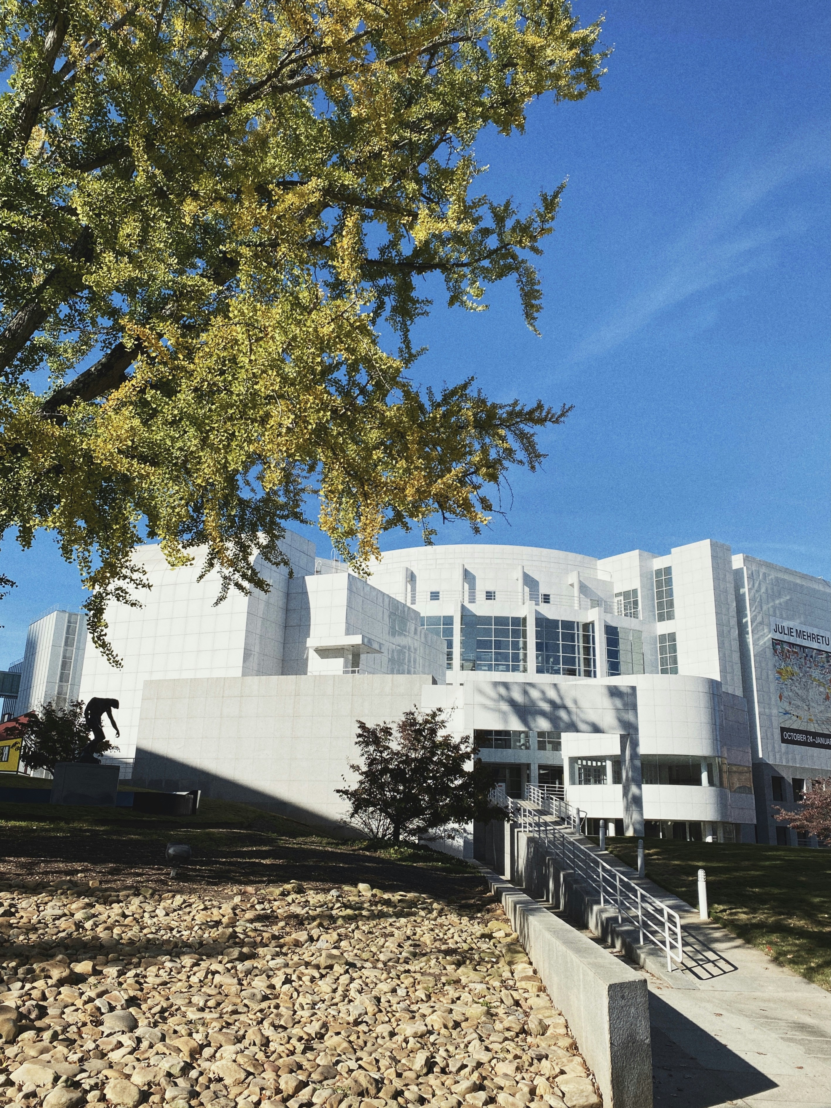 white concrete building near green tree under blue sky during daytime