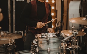 man in black long sleeve shirt playing drum