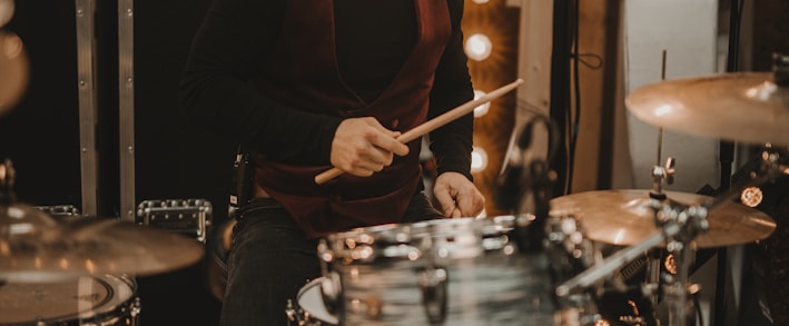 man in black long sleeve shirt playing drum