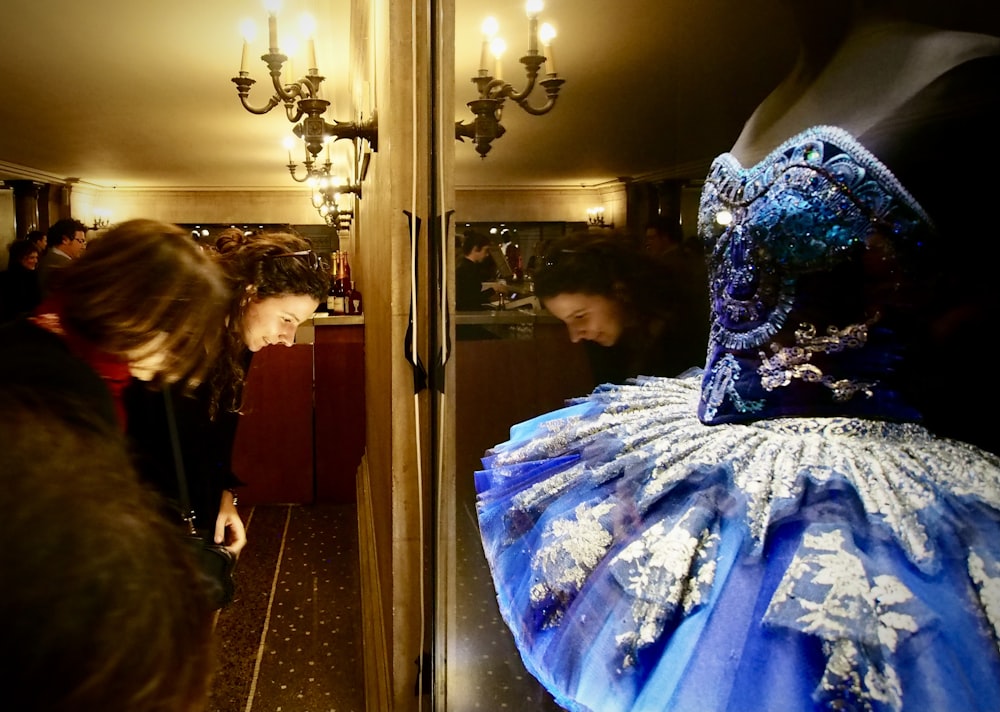 woman in white and blue floral dress standing beside mirror