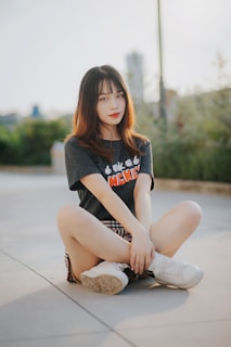 woman in gray sweater and white pants sitting on gray concrete floor