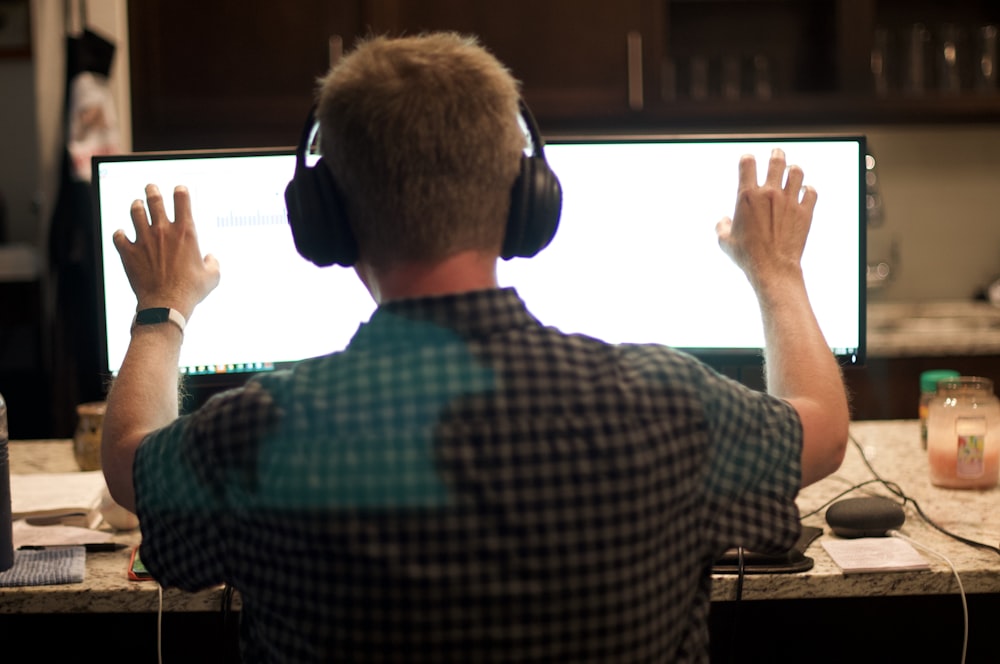 man in blue and white plaid shirt wearing black headphones