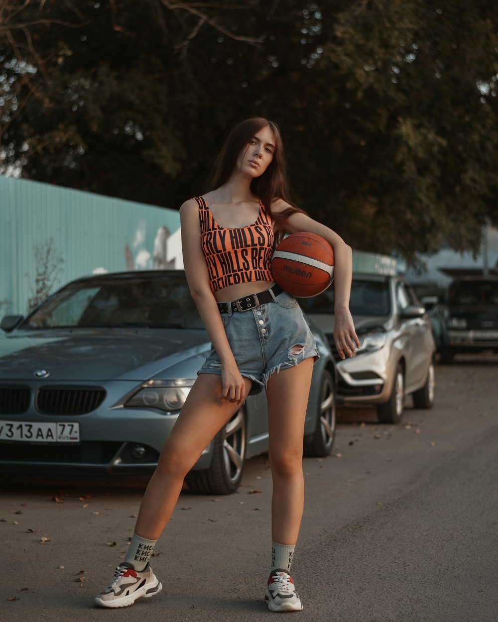 woman in red and white tank top and blue denim shorts holding basketball