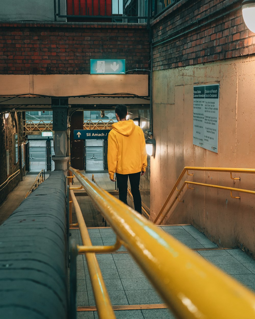 man in yellow jacket walking on train station during daytime