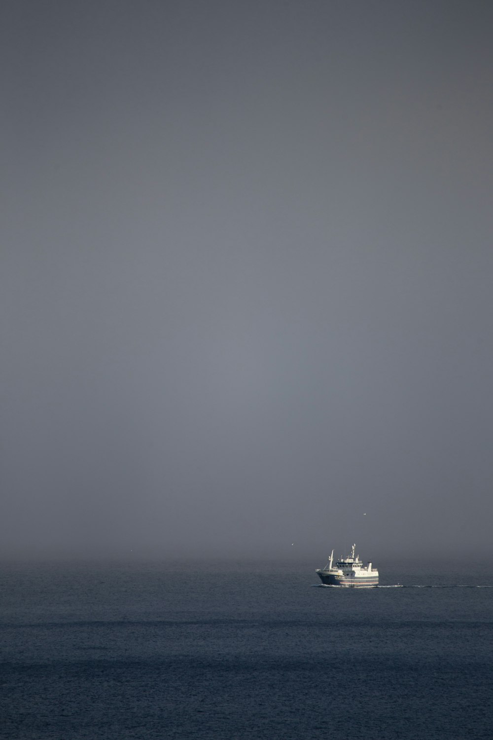 barca bianca sul mare sotto il cielo bianco durante il giorno