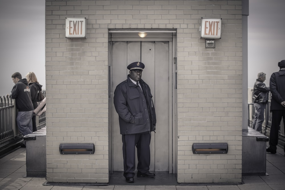 man in blue jacket standing near brown wooden door