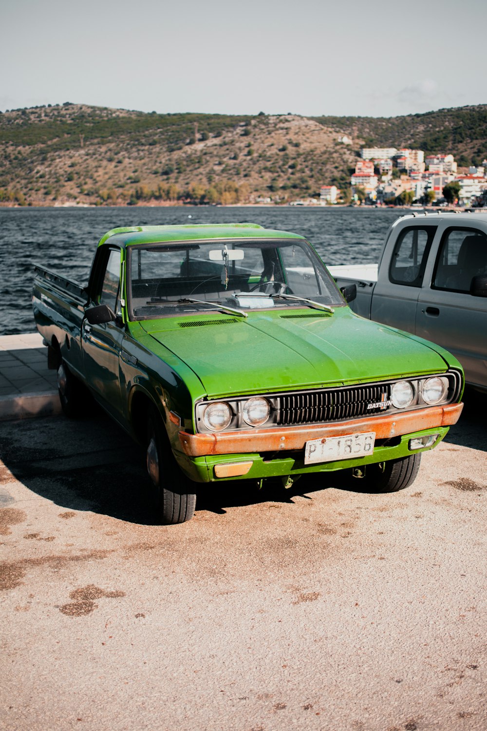 green car parked near body of water during daytime