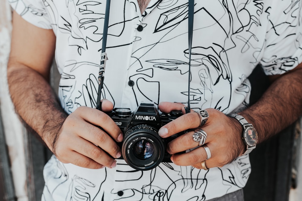 man in white button up shirt holding black nikon dslr camera