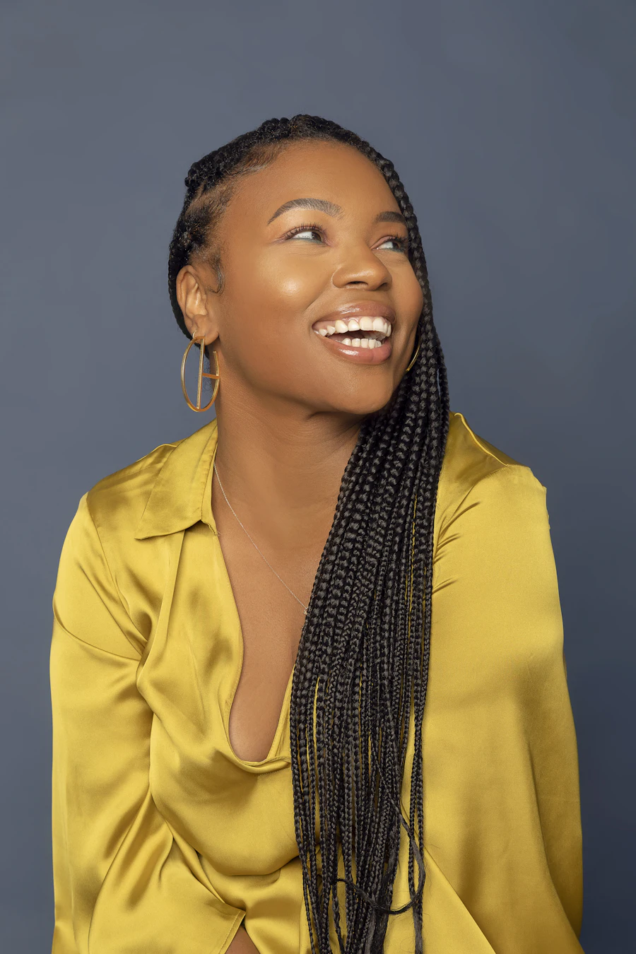 Woman in a yellow satin shirt wearing long knotless braids past her shoulder