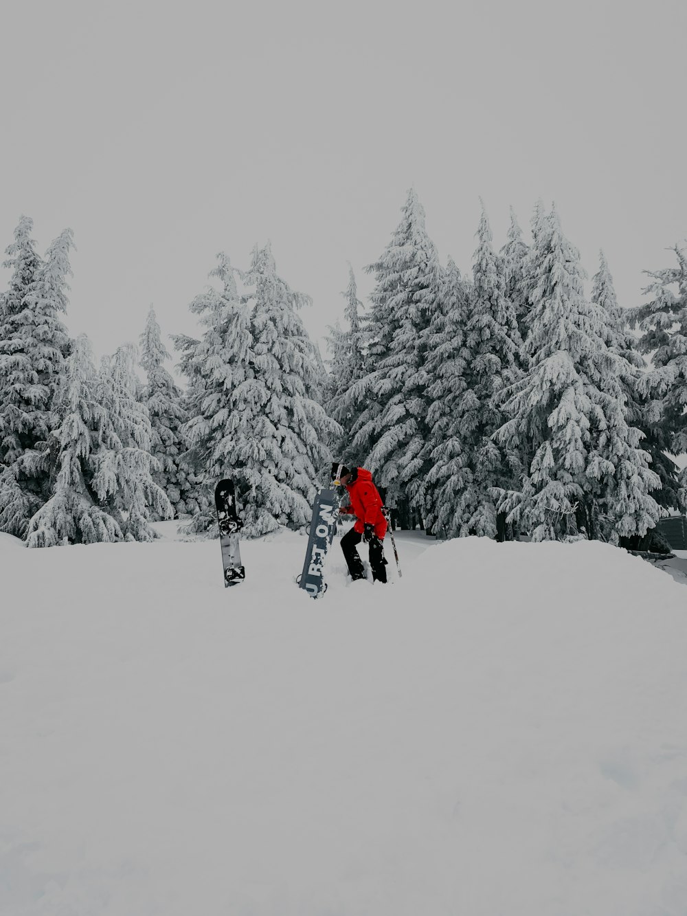 person in red jacket and black pants walking on snow covered ground during daytime