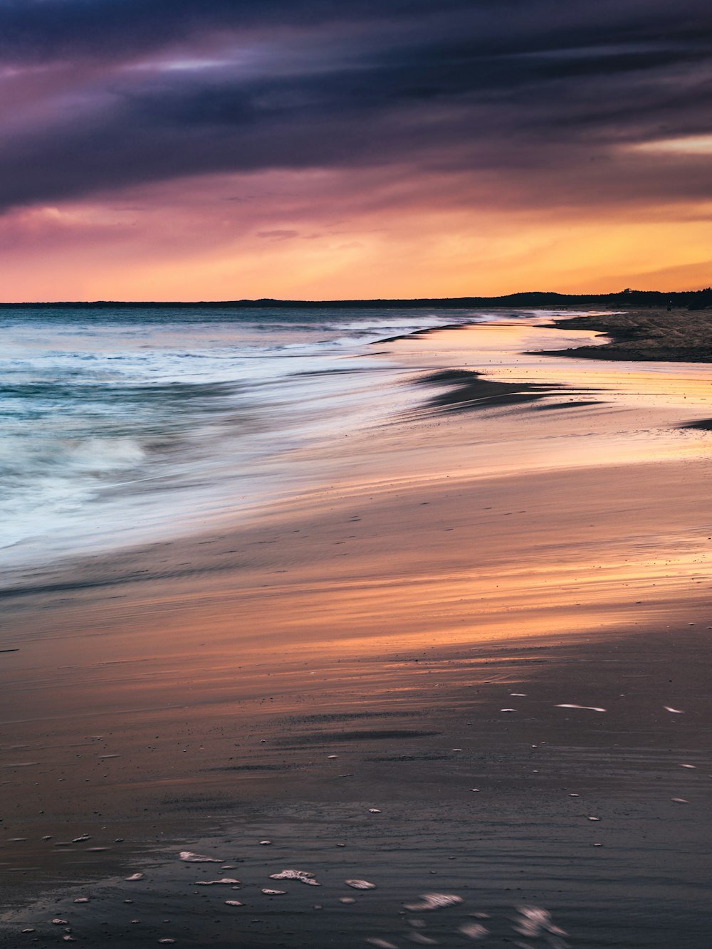 ocean waves crashing on shore during sunset