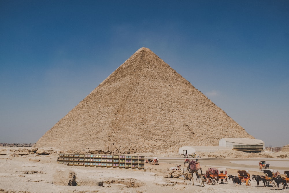 people walking on sand near pyramid during daytime