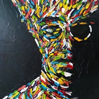 A vibrant abstract painting depicts a human face composed of bold, colorful brush strokes against a dark background. The colors include red, blue, green, yellow, and white, creating a dynamic and energetic appearance. The lines and colors form an impressionistic portrait with an impression of motion and vitality.