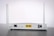 A white Wi-Fi router with two antennas positioned vertically. The router is seen from the back, showing ports and connectors including Ethernet ports, a power switch, and a power input. The device is placed on a dark surface against a light background.