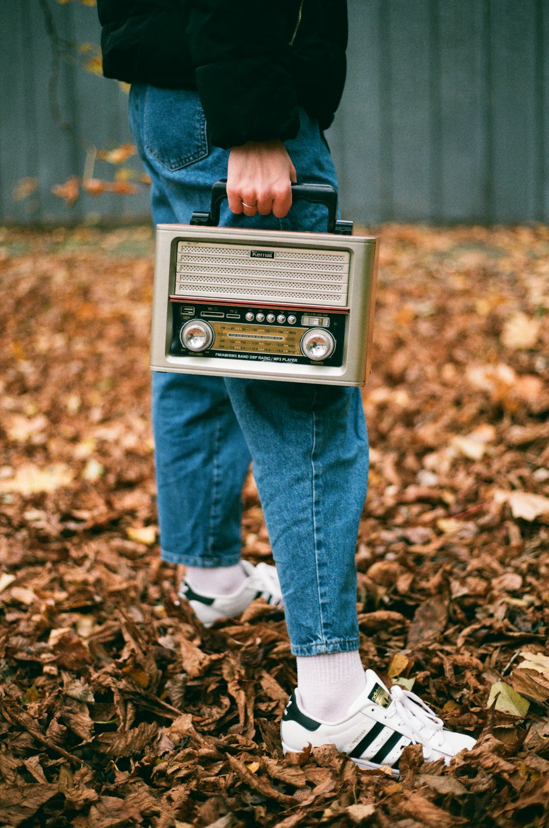  person in blue denim jeans and white socks standing on dried leaves during daytime radio