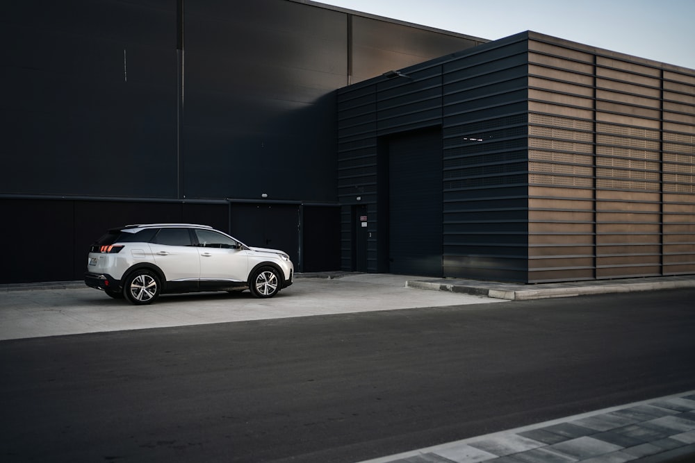 white coupe parked beside gray building