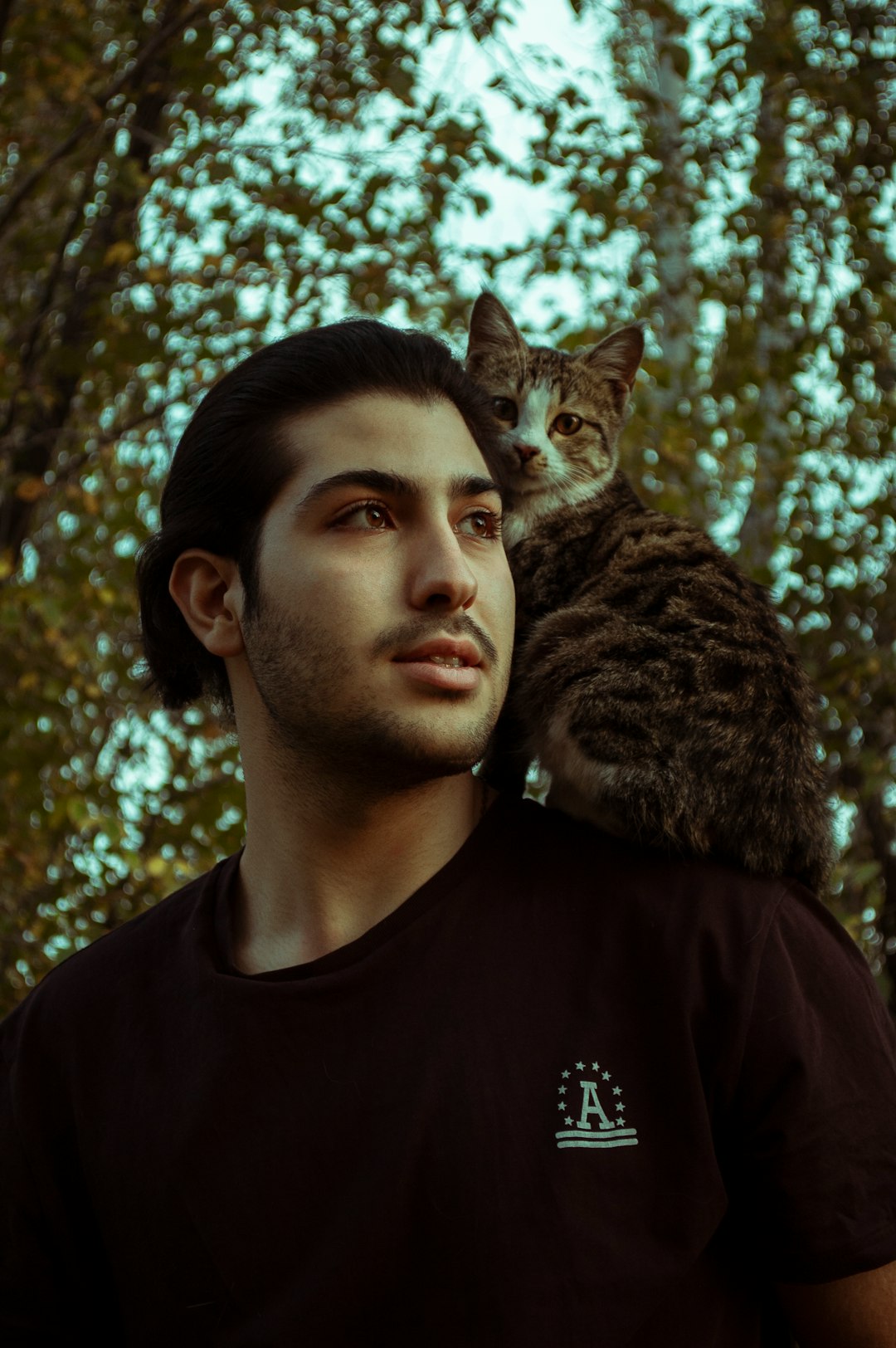 man in black crew neck shirt carrying brown tabby cat