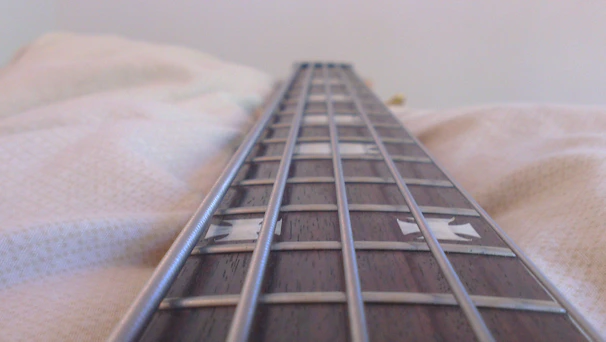 Artistic shot of a bass guitar neck with polished frets and vibrant inlays.