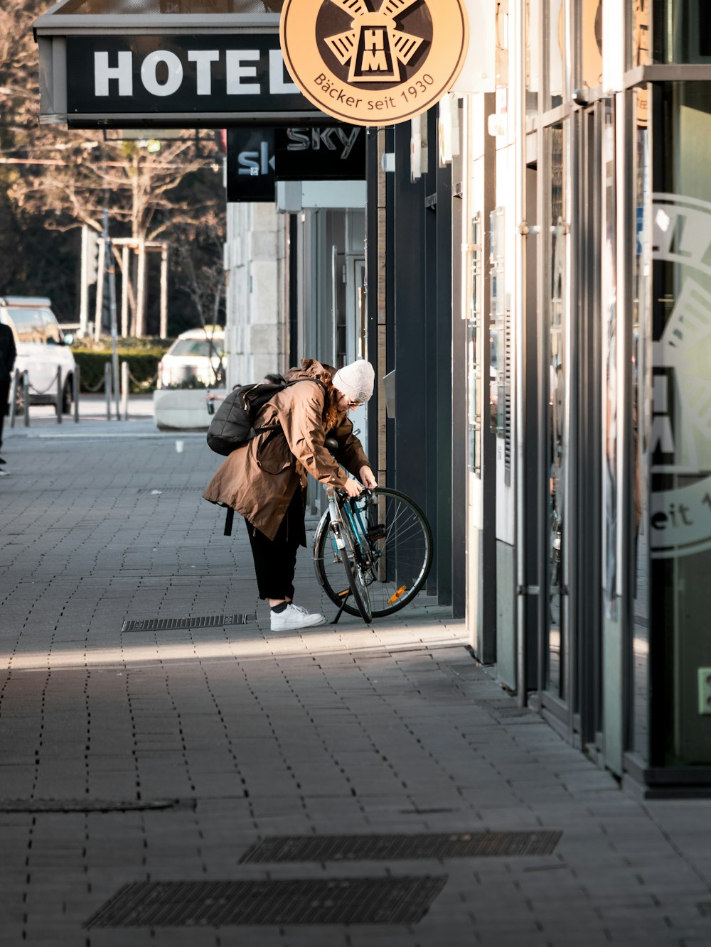 woman in brown coat and black pants walking on sidewalk during daytime