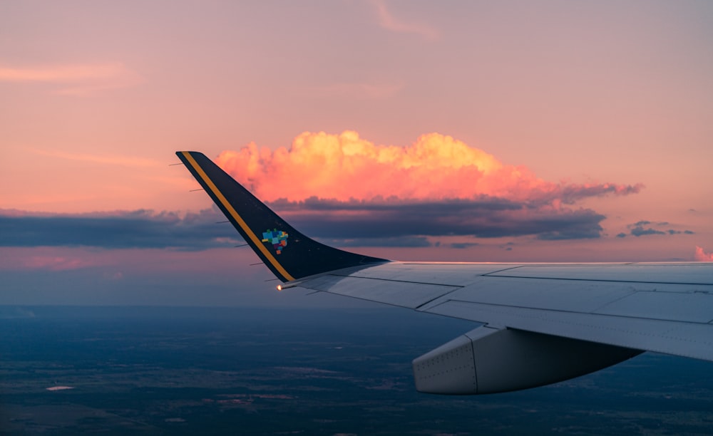 white and black airplane wing over white clouds during daytime