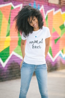 woman in white crew neck t-shirt and blue denim jeans standing on road during daytime