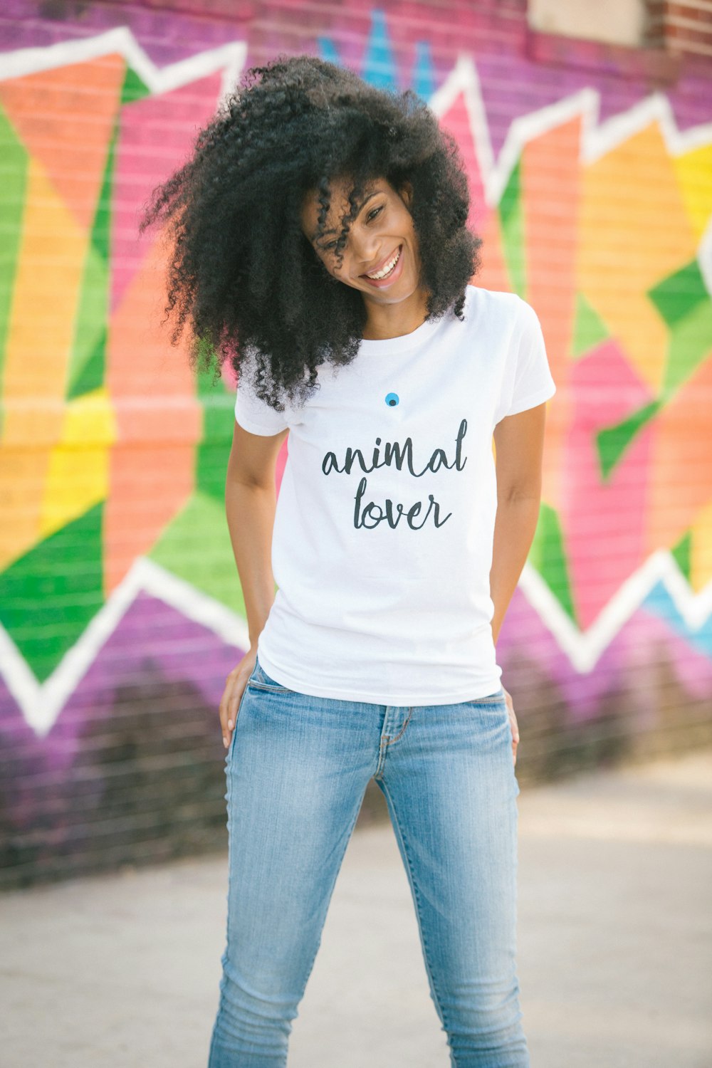 woman in white crew neck t-shirt and blue denim jeans standing on road during daytime