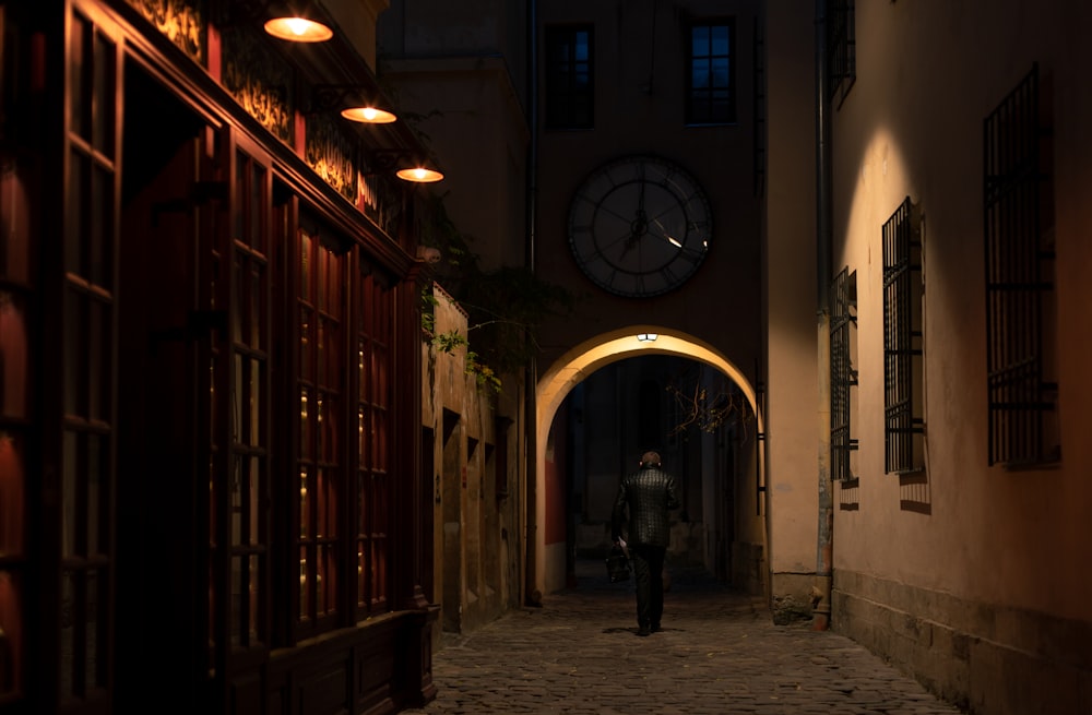 uomo in giacca nera che cammina sulla strada durante il giorno