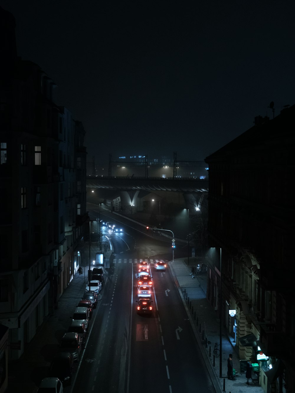 cars on road between high rise buildings during night time