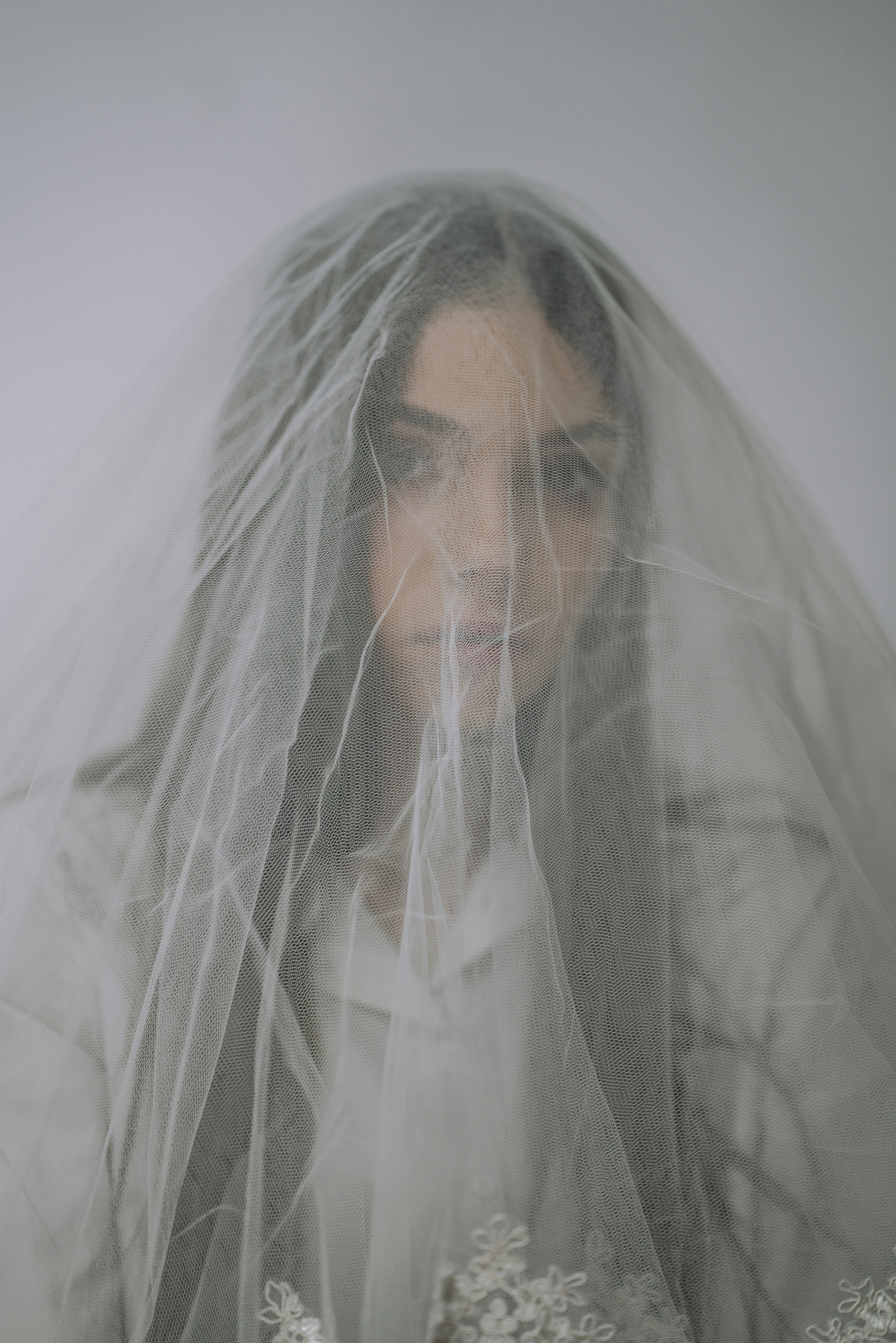 man-in-white-veil-covering-his-face-with-white-textile