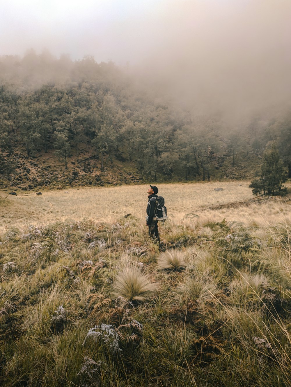 man in black jacket walking on brown grass field during daytime