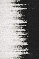 Abstract visual comprising a textured pattern where white fades into black, resembling static or a noise effect.