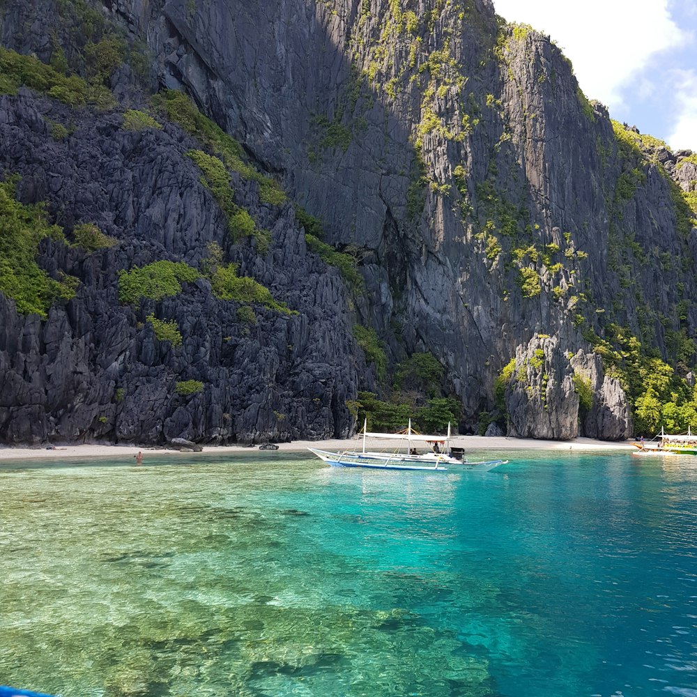 a boat floating on top of a body of water near a mountain