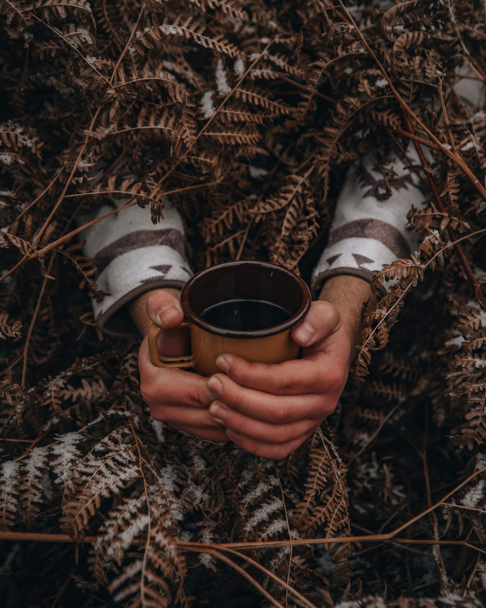 person holding brown ceramic mug