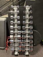 Row of shiny chrome barbells lined up on a rack in a bright fitness studio.