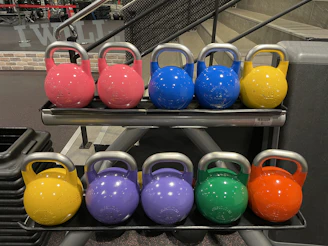 A set of colorful kettlebells lined up on the gym floor, ready for a dynamic workout.