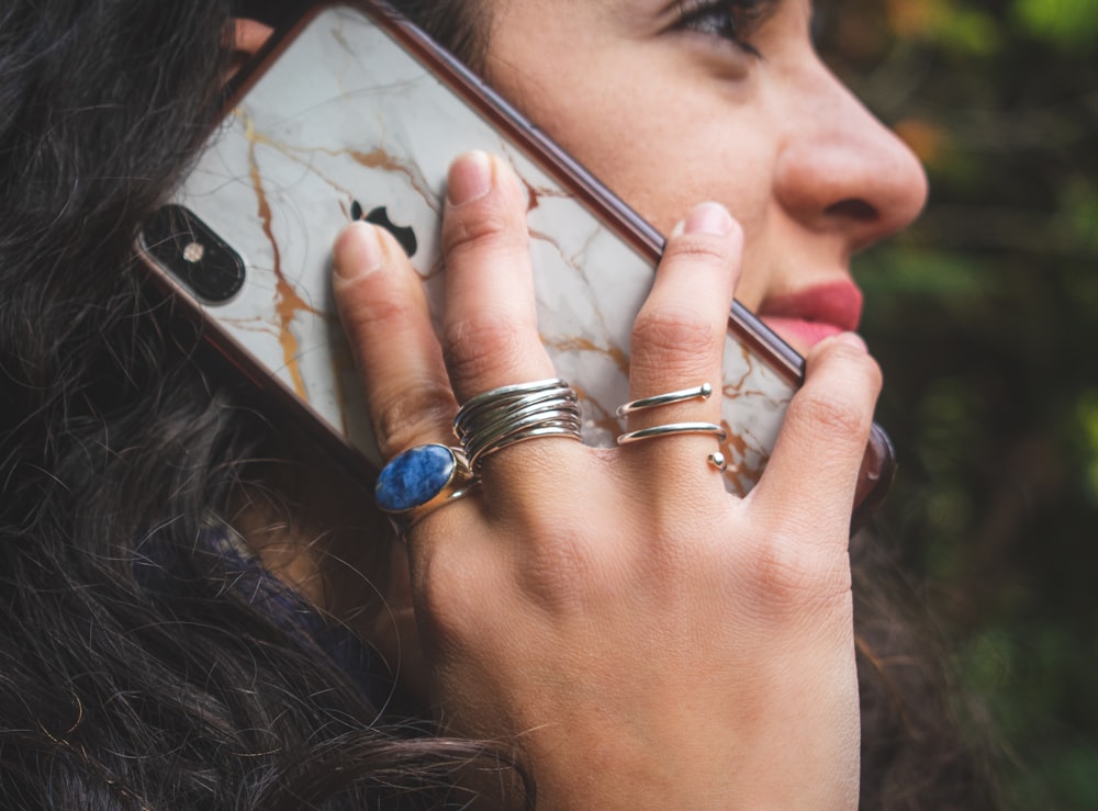 Mujer con anillo de oro sosteniendo iPhone 6 plateado