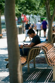A happy user comfortably using a mobile app on a park bench.