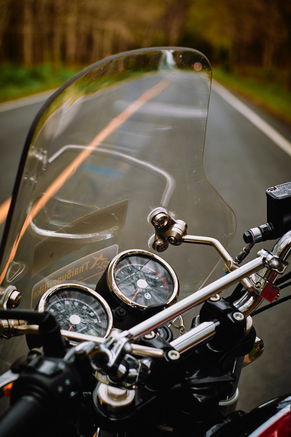 昼間の道路を走る黒と銀のバイク