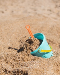 red plastic shovel on sand