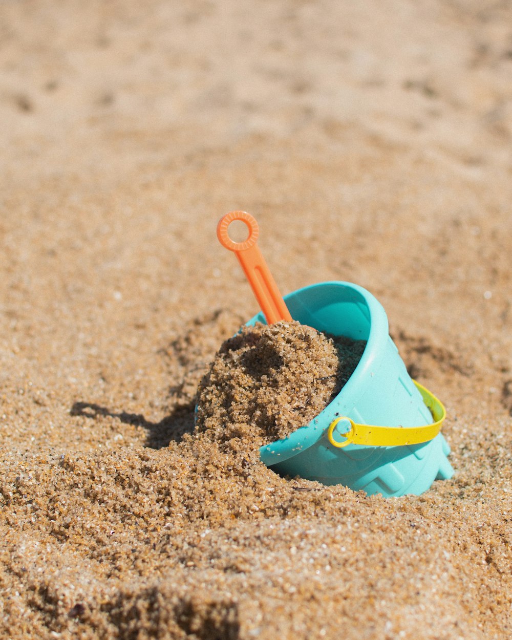 red plastic shovel on sand