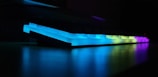 Close-up of a sleek mechanical keyboard with customizable RGB lighting glowing in a dark room.
