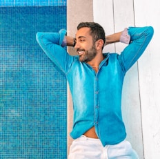 man in blue zip up jacket leaning on blue wall