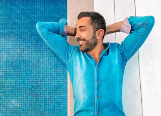 man in blue zip up jacket leaning on blue wall